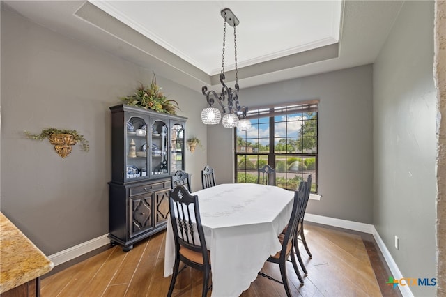 1448 Decanter Dr, New Braunfels, TX 78132 - dining space featuring wood finished floors, a raised ceiling, a chandelier, and ornamental molding