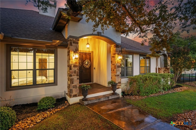 1448 Decanter Dr, New Braunfels, TX 78132 - exterior entry at dusk featuring stone siding, stucco siding, and a shingled roof