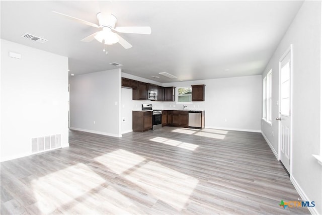 unfurnished living room featuring ceiling fan, sink, and light wood-type flooring