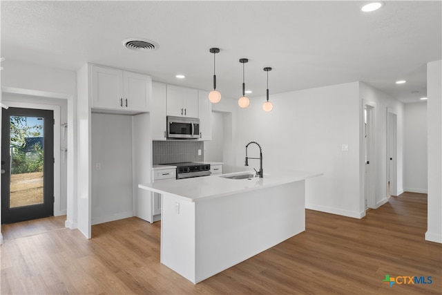 kitchen with light hardwood / wood-style floors, sink, appliances with stainless steel finishes, a kitchen island with sink, and white cabinets