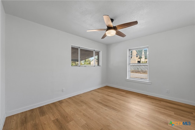 empty room featuring light wood-type flooring, a textured ceiling, and ceiling fan