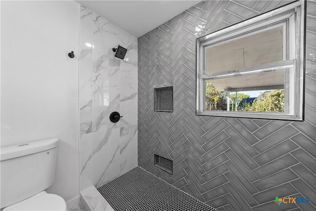 bathroom featuring toilet and a tile shower