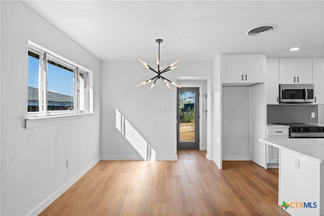 kitchen with tasteful backsplash, white cabinets, a healthy amount of sunlight, and stainless steel appliances