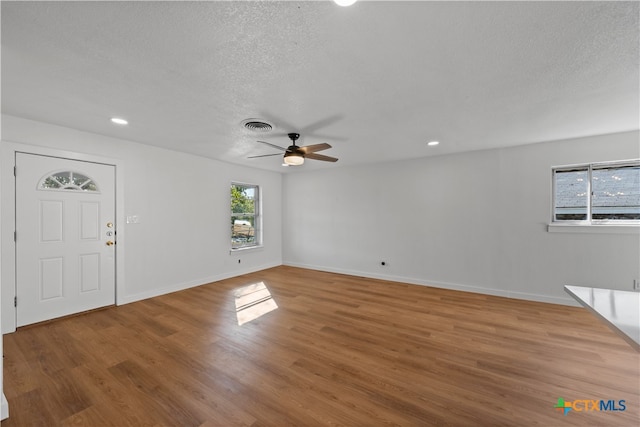 foyer entrance featuring a textured ceiling, hardwood / wood-style floors, a healthy amount of sunlight, and ceiling fan