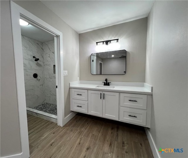 bathroom with a tile shower, vanity, and hardwood / wood-style flooring