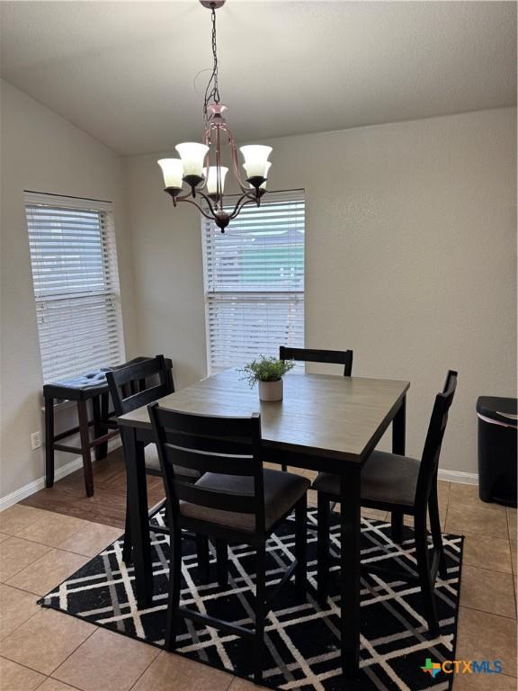 dining room featuring lofted ceiling, light tile patterned floors, baseboards, and a healthy amount of sunlight