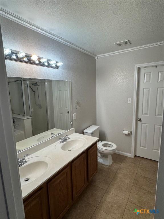 bathroom featuring a textured ceiling, a stall shower, a sink, and visible vents