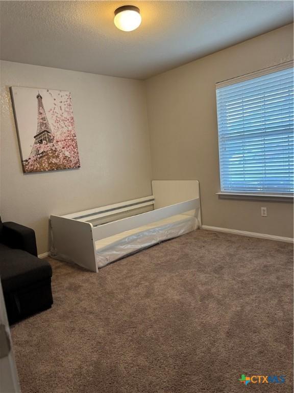 carpeted bedroom featuring baseboards and a textured ceiling