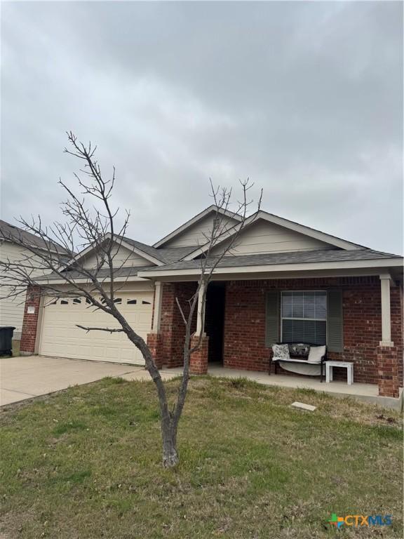 single story home with a garage, driveway, a front lawn, and brick siding