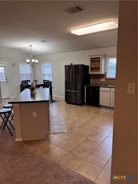 kitchen with dark countertops, black appliances, light tile patterned floors, and visible vents