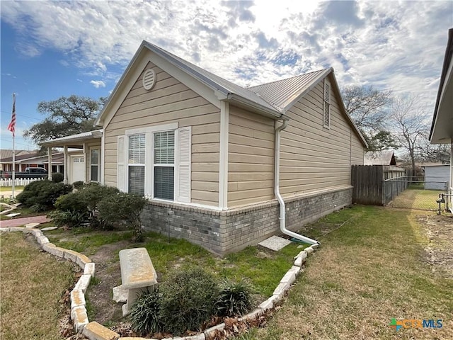 view of side of property featuring a yard, brick siding, and fence