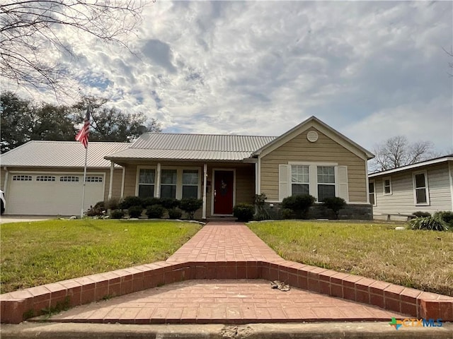 ranch-style house with metal roof, an attached garage, and a front yard