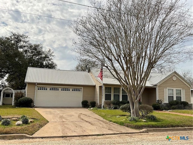 ranch-style home with a garage, a front yard, concrete driveway, and metal roof