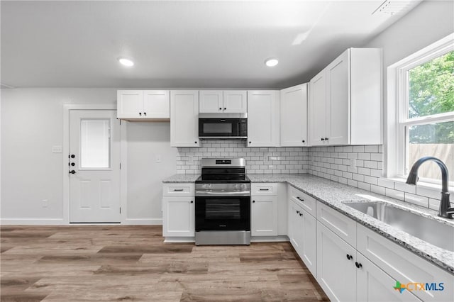 614 S 24th St, Temple, TX 76501 - kitchen with electric stove, a sink, white cabinetry, light wood-style floors, and backsplash