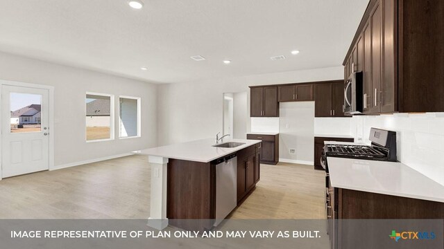 193 Zane Saddle Rd, Lockhart, TX 78644 - kitchen featuring a sink, an island with sink, light wood-style floors, dark brown cabinetry, and appliances with stainless steel finishes