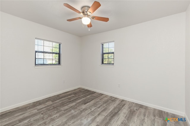 unfurnished room featuring a ceiling fan, wood finished floors, and baseboards