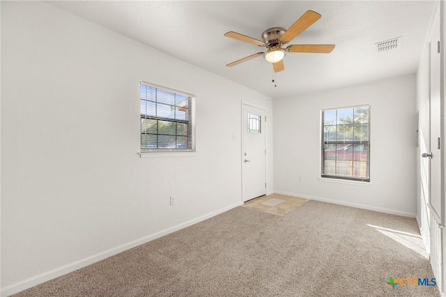 empty room featuring baseboards, visible vents, a wealth of natural light, and light carpet