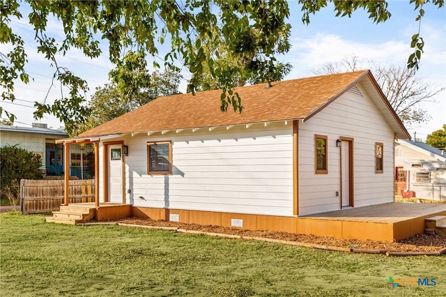 back of property with crawl space, a yard, roof with shingles, and fence