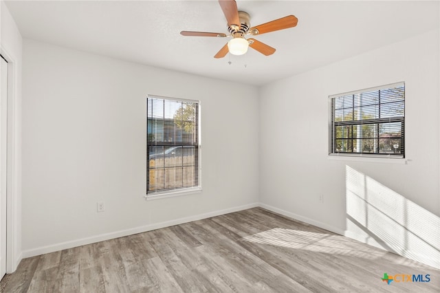 unfurnished room with baseboards, light wood-style floors, and a ceiling fan