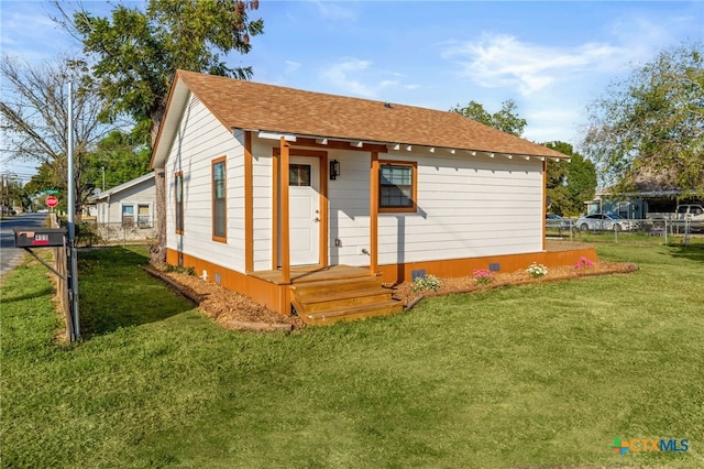 back of house with a yard, fence, and roof with shingles