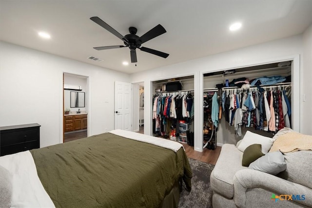 bedroom featuring sink, two closets, dark hardwood / wood-style floors, and ceiling fan