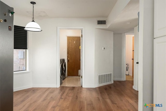 empty room with hardwood / wood-style flooring and washing machine and clothes dryer