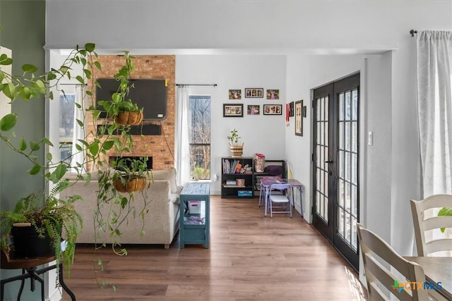 living area with french doors, wood-type flooring, and a brick fireplace