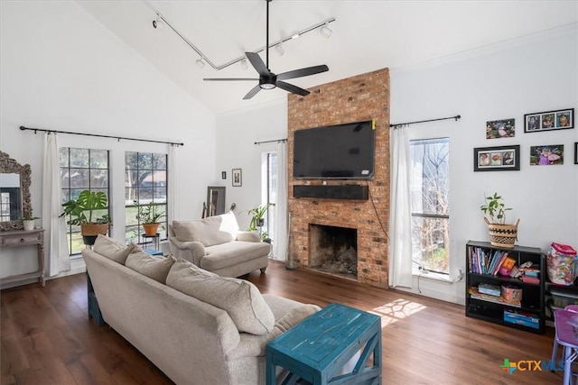 living room with high vaulted ceiling, track lighting, dark hardwood / wood-style floors, ceiling fan, and a fireplace