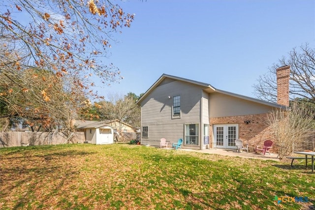 rear view of house with french doors, a storage shed, a patio area, and a lawn