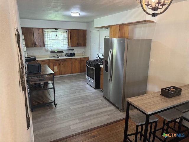 4912 Evergreen Ln, Victoria, TX 77904 - kitchen with appliances with stainless steel finishes, light countertops, light wood-style floors, a chandelier, and brown cabinetry