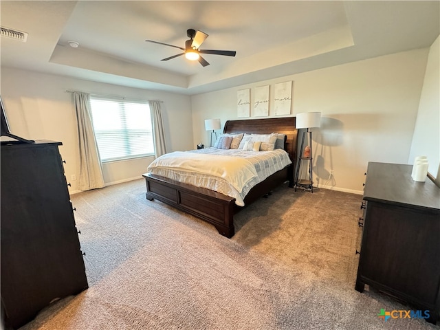 carpeted bedroom with ceiling fan and a raised ceiling