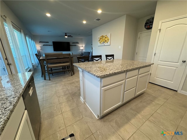 kitchen featuring light stone countertops, ceiling fan, light tile patterned floors, a kitchen island, and white cabinets