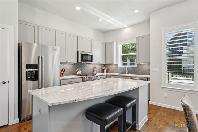 13900 Zink Bnd Unit 61, Austin, TX 78717 - kitchen with appliances with stainless steel finishes, a breakfast bar, tasteful backsplash, a sink, and light stone countertops