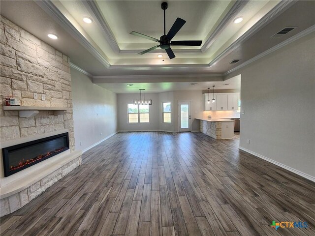 719 Eagle Claw Dr, Salado, TX 76571 - unfurnished living room with a tray ceiling, dark wood finished floors, crown molding, ceiling fan, and a stone fireplace