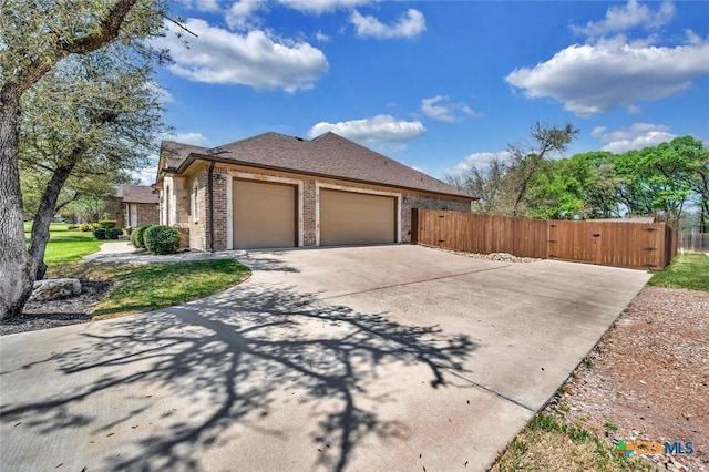 view of side of property featuring an attached garage, brick siding, fence, and concrete driveway