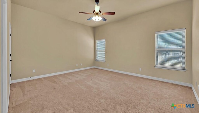 spare room featuring light colored carpet, ceiling fan, and baseboards