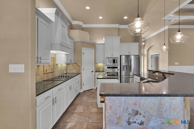 kitchen with decorative backsplash, ornamental molding, premium range hood, appliances with stainless steel finishes, and a large island