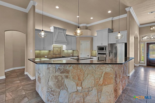 kitchen with backsplash, dark countertops, arched walkways, appliances with stainless steel finishes, and custom exhaust hood