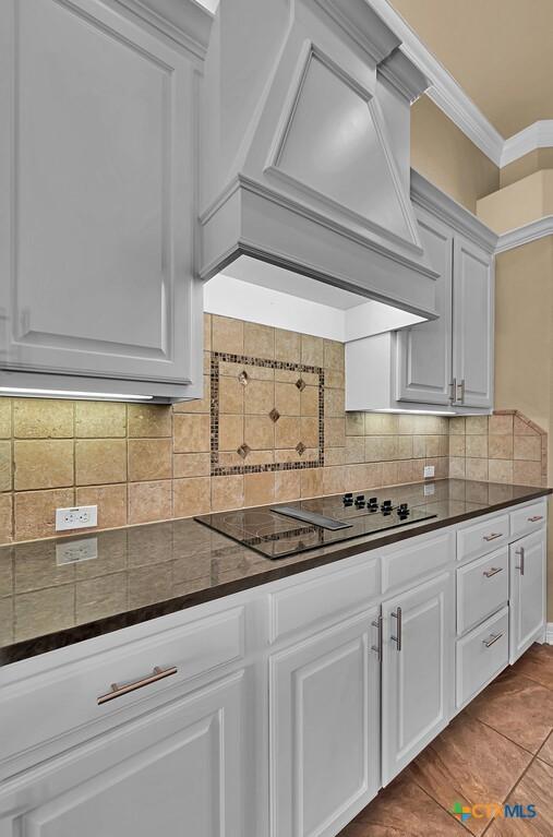 kitchen featuring white cabinetry, crown molding, and custom range hood