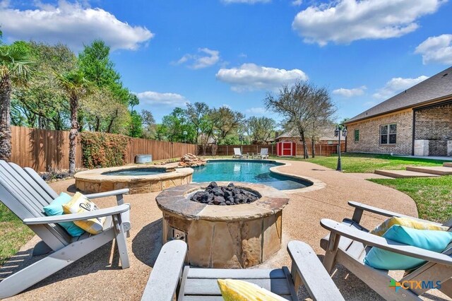 view of swimming pool with an in ground hot tub, an outdoor fire pit, an outdoor structure, a fenced backyard, and a storage unit