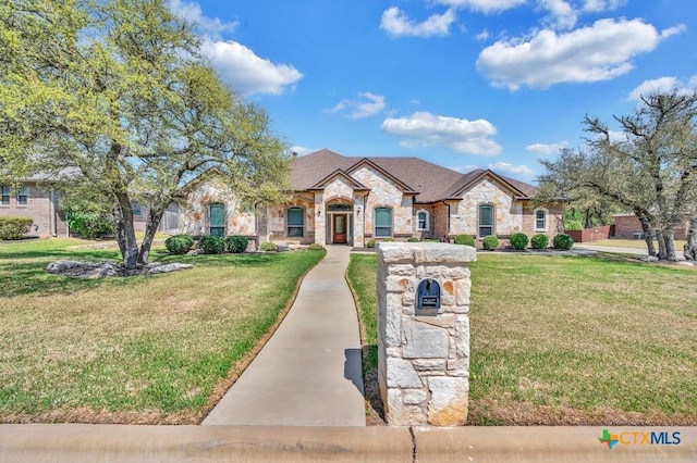 french country home with stone siding and a front lawn