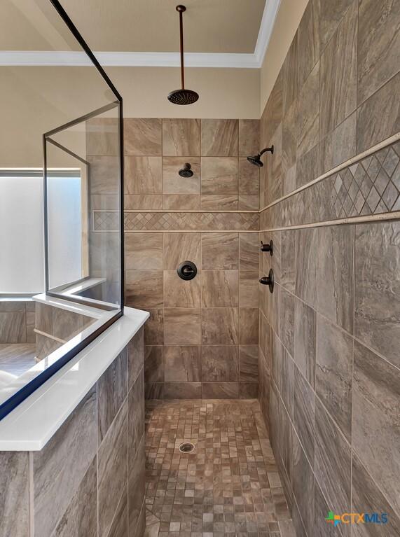bathroom with crown molding and a tile shower