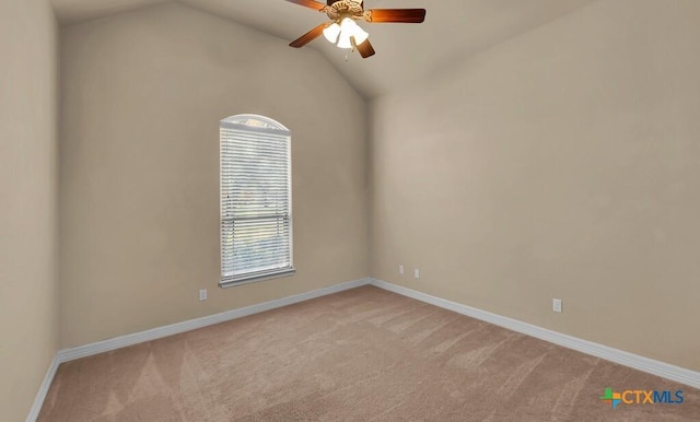 spare room featuring a ceiling fan, light carpet, baseboards, and vaulted ceiling