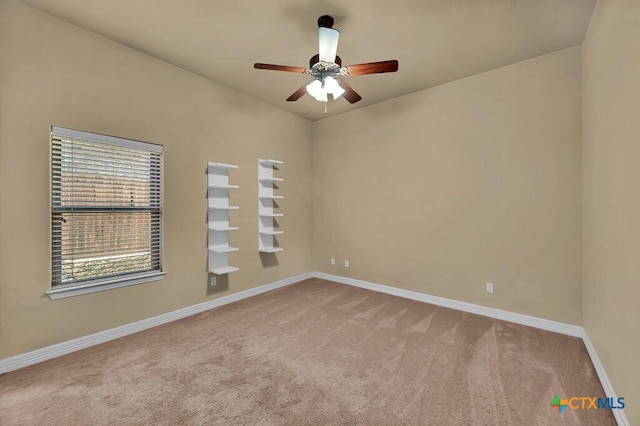 carpeted spare room featuring baseboards and ceiling fan