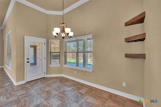 unfurnished dining area featuring a towering ceiling, a notable chandelier, crown molding, and baseboards