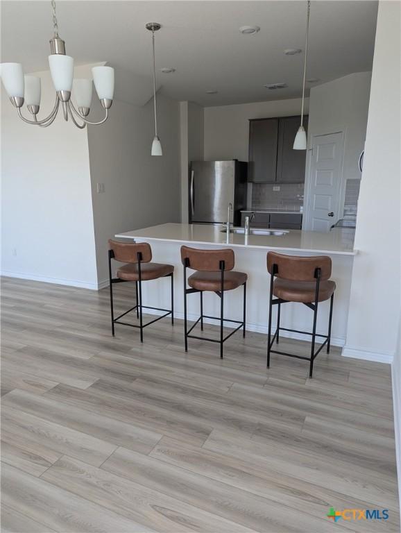 4177 Harper Lee Ln, New Braunfels, TX 78130 - kitchen with freestanding refrigerator, a kitchen breakfast bar, light countertops, and decorative backsplash