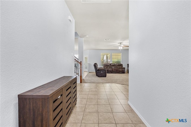 5920 Stonehaven Dr, Temple, TX 76502 - hall featuring stairs, light carpet, light tile patterned floors, a textured wall, and baseboards