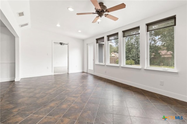 empty room featuring vaulted ceiling, dark tile patterned flooring, and ceiling fan