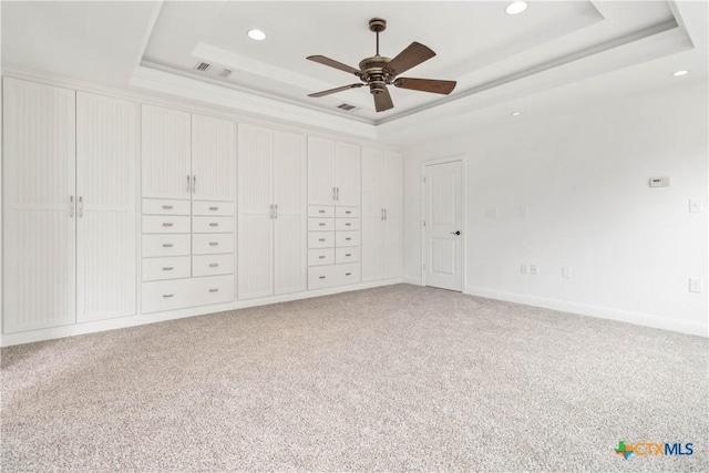 unfurnished bedroom with carpet floors, a raised ceiling, and ceiling fan