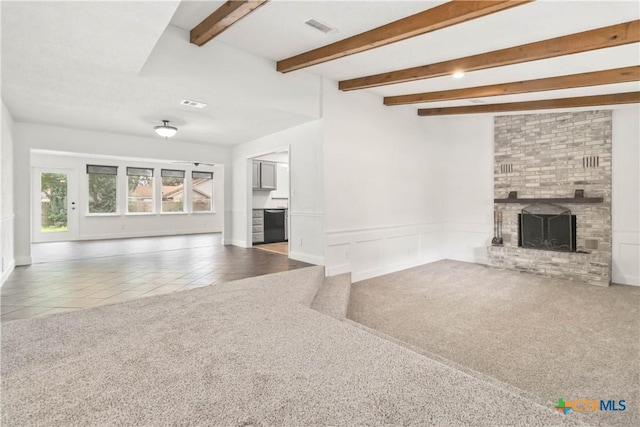 unfurnished living room with beamed ceiling, carpet flooring, and a brick fireplace